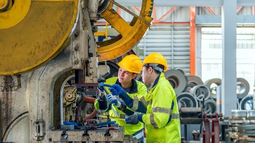 Image of two people working on a machine